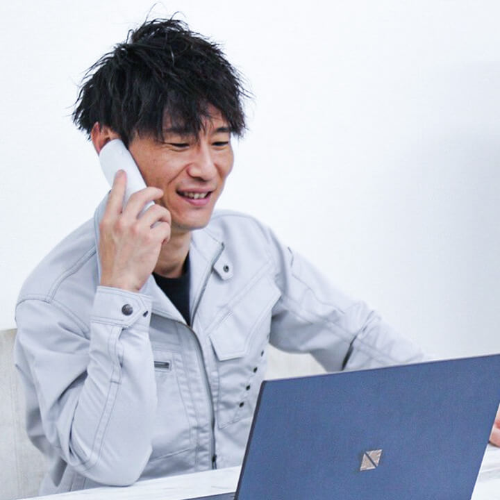 パソコンの前でにこやかに電話をかけるスタッフ