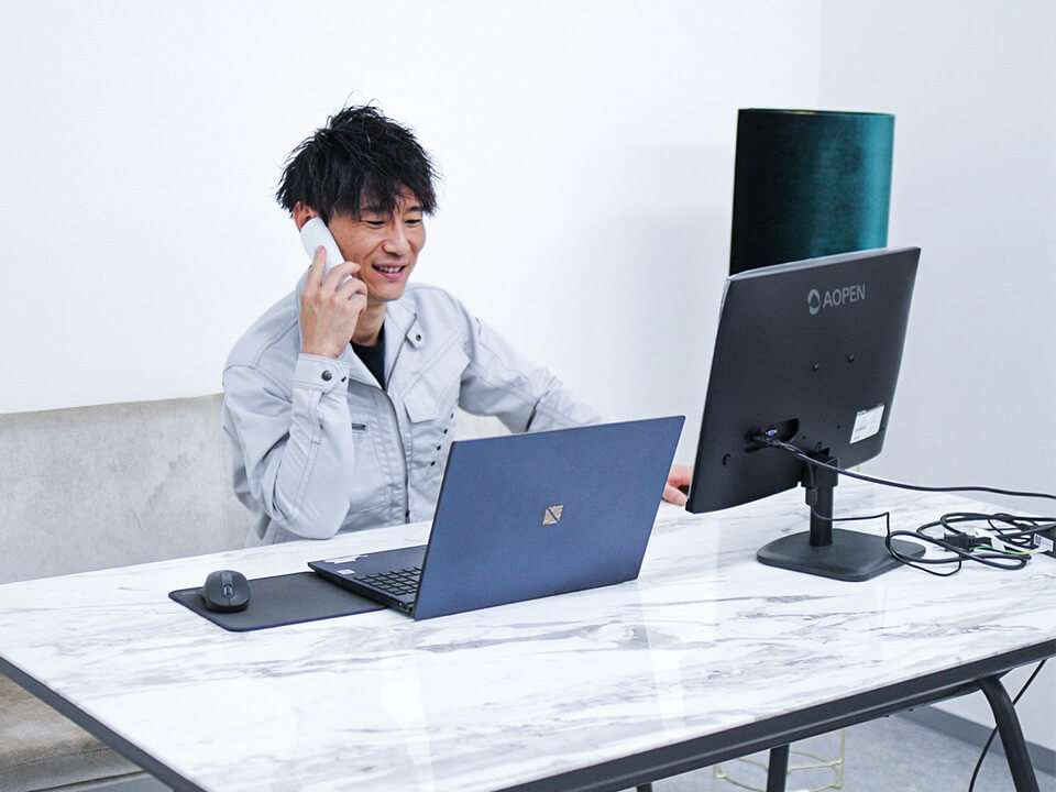 パソコンの前でにこやかに電話をかけるスタッフ